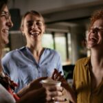 Two female colleagues laughing during a coffee break in office