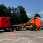 Red semi truck transporting an oversized wind turbine blade section