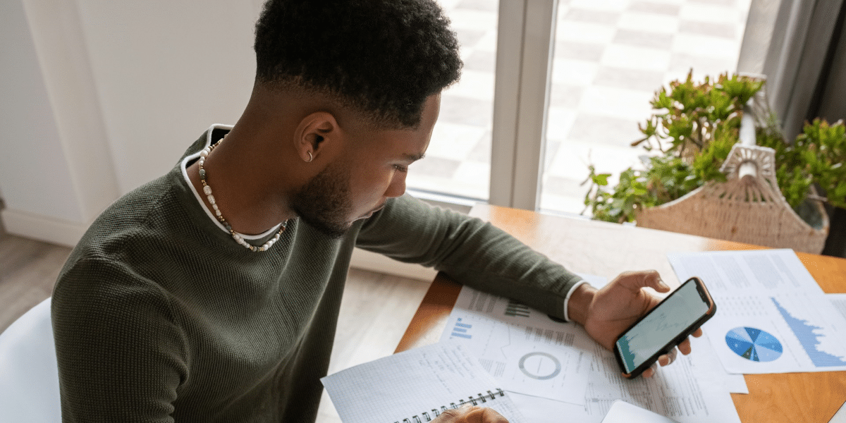 A focused individual engaged in financial planning with charts and a laptop, representing the strategic debt management services provided by National Debt Relief for achieving financial stability.